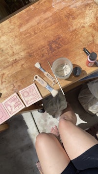 a person sitting on a wooden table with a paint brush