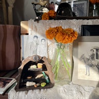a vase of orange flowers sits on a table next to a picture of a horse