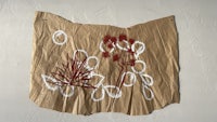 a piece of brown paper with red and white drawings on it